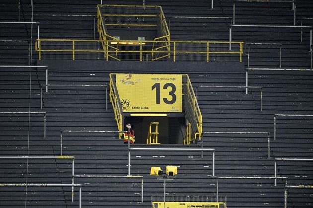 Steward na jinak opuštěné tribuně sleduje přípravy na derby Dortmund - Schalke.