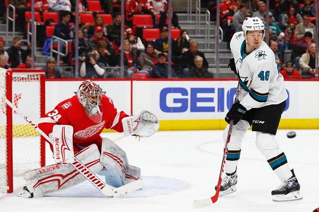 Tomáš Hertl ze San Jose zkouší tečovat střelu před brankářem Detroitu Petrem Mrázkem.