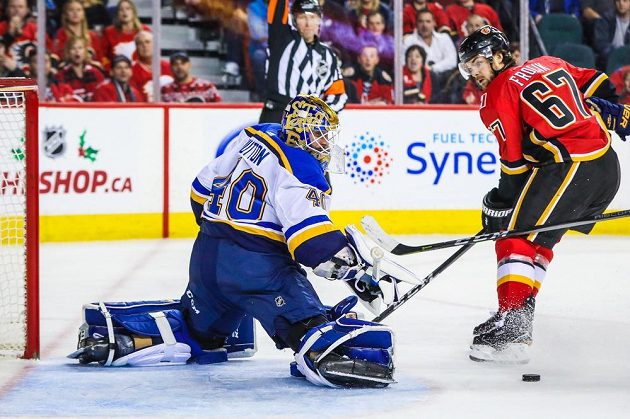 Michael Frolík, český útočník ve službách Calgary Flames, před brankářem Carterem Huttonem ze St. Louis.