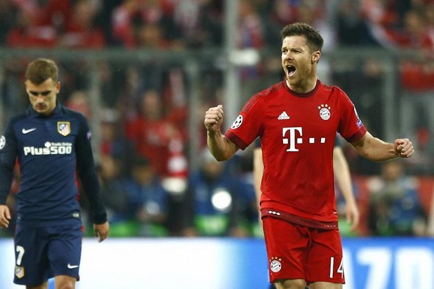 Xabi Alonso poslal Bayern do vedení. Vlevo je zklamaný útočník Colchoneros Antoine Griezmann.