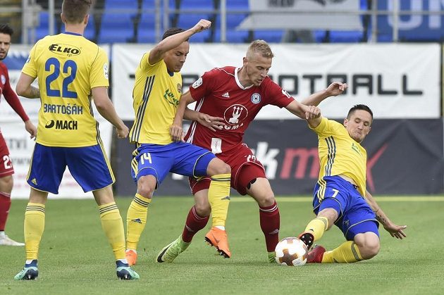 Zlínští fotbalisté Lukáš Bartošák a Daniel Holzer se snaží zastavit olomouckého Uroše Radakoviče. Situaci v utkání 28. kola HET ligy přihlíží Lukáš Železník ze Zlína.