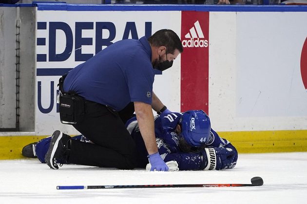 Zraněný český hokejista Jan Rutta leží na ledě během pátého semifinále play off NHL. Pomoci se mu snaží Tom Mulligan.
