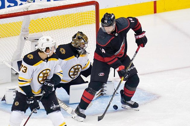 Křídelník Caroliny Hurricanes Justin Williams (14) zkouší tečovat puk před brankou Bostonu Bruins, kterou střežil slovenský gólman Jaroslav Halák (41).