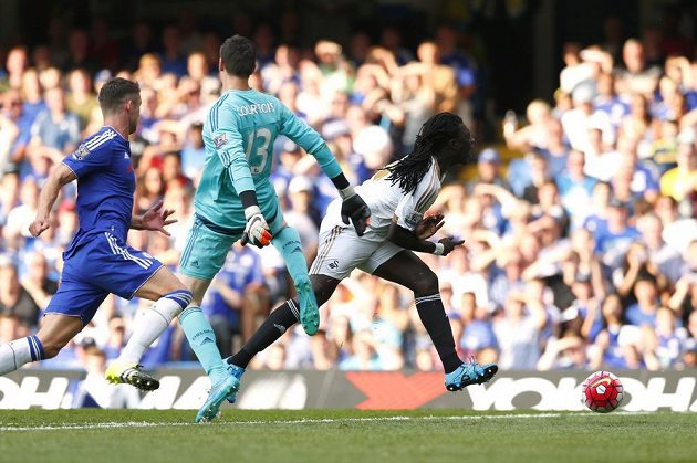Útočník Swansea Bafetimbi Gomis padá po kontaktu s brankářem Thibautem Courtoisem.