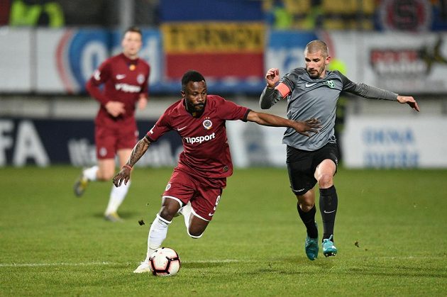 Sparťanský záložník Guélor Kanga vede míč v utkání v Příbrami. Atakovat se jej chystá zkušený Jan Rezek.