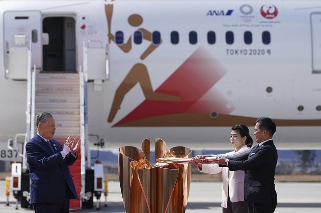 Olympijský oheň je v Japonsku. Trojnásobný olympijský vítěz Tadahiro Nomura (vlevo) a držitelka tří zlatých medailí Saori Jošidaová s olympijským ohněm po příletu do pořadatelské země olympiády. Šéf organizačního výboru Jošihiro Mori (vlevo).