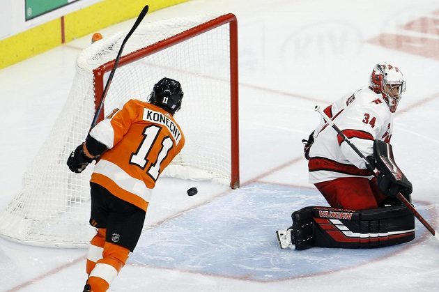 Hokejista Philadelphie Flyers Travis Konecny (11) překonává Petra Mrázka v brance Caroliny.