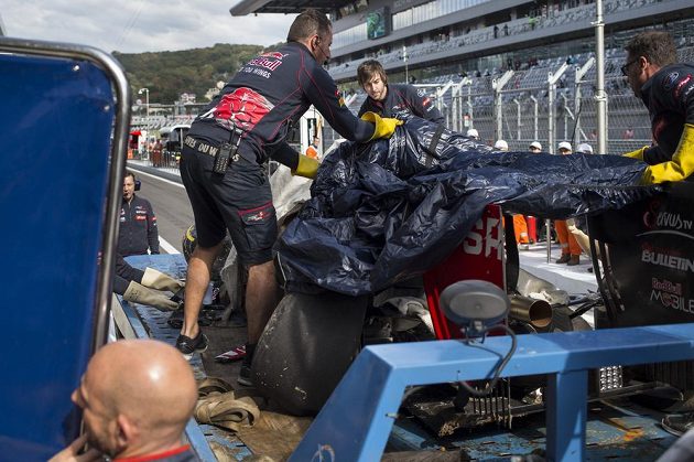 Mechanici stáje Toro Rosso v boxech odkrývají zničenou formuli Carlose Sainze.