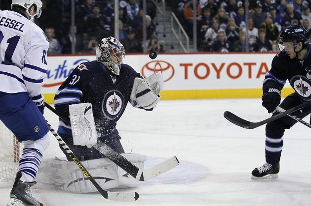 Brankář Winnipegu Ondřej Pavelec se natahuje po puku v utkání s Torontem.