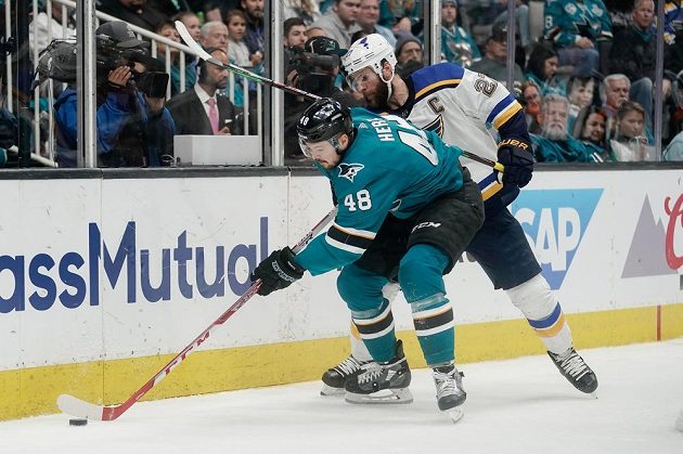 Tomáš Hertl ze San Jose Sharks vede puk podél mantinelu před obráncem St. Louis Blues Alexem Pietrangelem během pátého zápasu semifinálové série NHL.