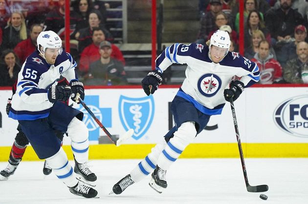 Mark Scheifele (vlevo) a finský rychlík Patrick Laine rozjíždějí akci Winnipegu v utkání NHL na ledě Caroliny.