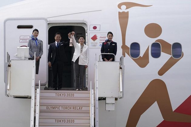 Olympijský oheň je v Japonsku. Trojnásobný olympijský vítěz Tadahiro Nomura (vlevo) a držitelka tří zlatých medailí Saori Jošidaová s olympijským ohněm po příletu do pořadatelské země olympiády.
