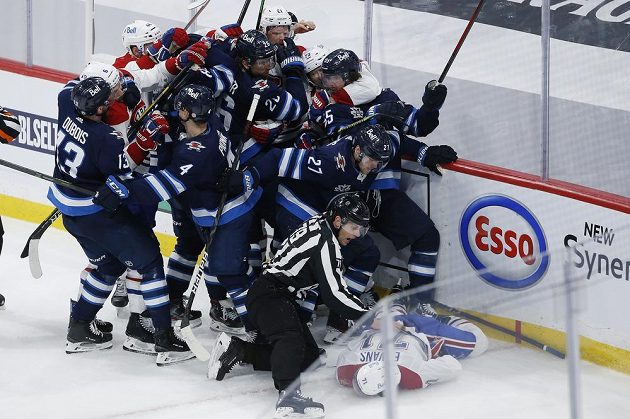 Zraněný útočník Montrealu Canadiens Jake Evans (71) leží zraněný na ledové ploše po zákroku Marka Scheifeleho (55) z Winnipegu Jets během utkání play off NHL. Na ledě se strhla okamžitě rvačka.