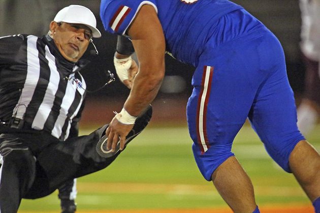 Referee Fred Gracia falls to the ground after being attacked by one of the players during an American football game.  The referee ended up in the hospital, the incident is being investigated by the police.