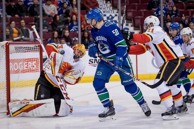 Brankář David Rittich (33) při zákroku proti Vancouveru před Brendanem Gauncem (50) z Vancouveru a Mikaelem Backlundem (11) z Calgary.