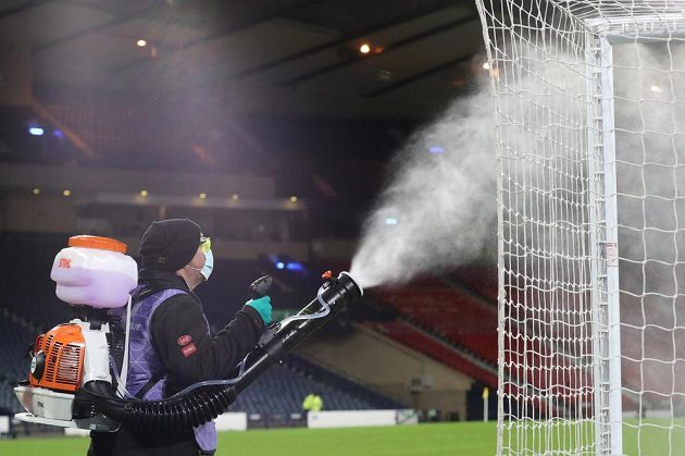 Jeden z pořadatelů dezinfikuje vybavení hřiště před utkáním Skotsko - ČR v Hampden Parku.