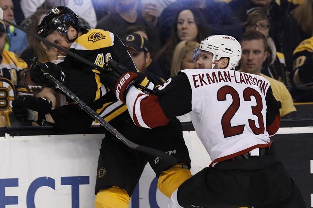 Obránce Arizony Coyotes Oliver Ekman-Larsson přišpendlil na mantinel českého útočníka Davida Krejčího z týmu Boston Bruins v utkání NHL.