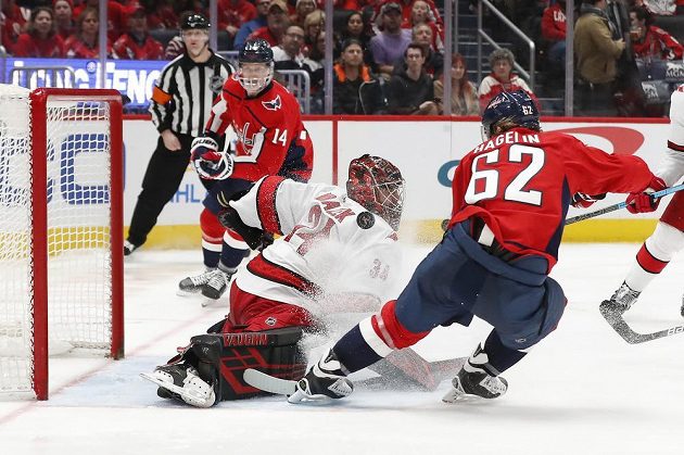 Brankář Caroliny Hurricanes Petr Mrázek (34) zasahuje proti křídelníkovi Washingtonu Capitals Carlu Hagelinovi (62).