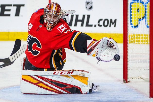 Český brankář Calgary Flames David Rittich (33) se natahuje po puku v utkání NHL.