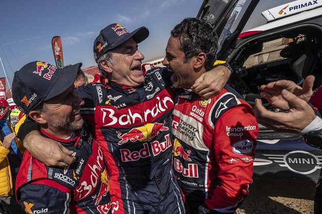 Španěl Carlos Sainz (uprostřed) přijímá gratulace od Francouze Stephane Peterhansela (vlevo) a Katařana Nassera Al-Attiyaha v cíli dakarské rallye.