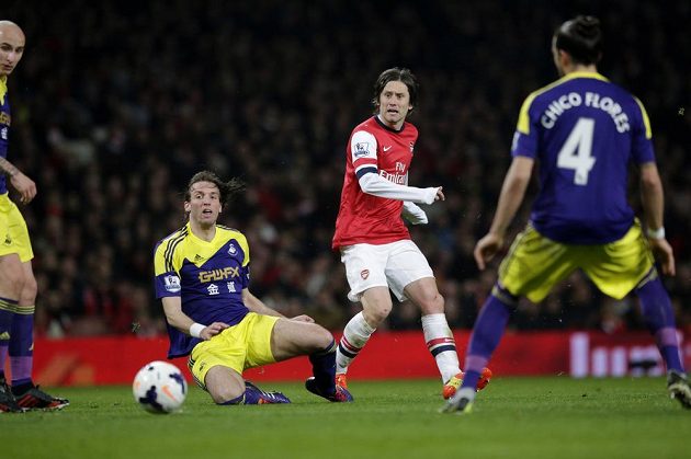 Záložník Arsenalu Tomáš Rosický (uprostřed) přihrává míč mezi hráči Swansea City Michuem (na zemi) a Chico Floresem.