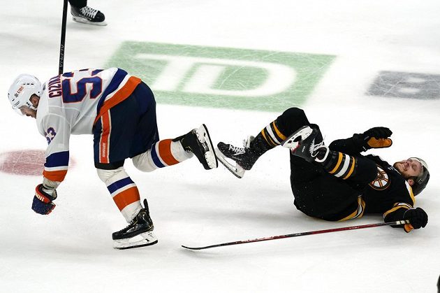 Hvězdný útočník Bostonu Bruins David Pastrňák skončil na lopatkách po souboji s Casey Cizikasem (53) z týmu New York Islanders během utkání NHL.