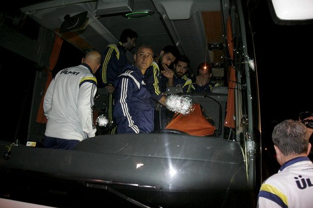 Hráči Fenerbahce Emre Belezöglu, Alper Potuk, Bekir Irtegün a trenér Ismail Kartal si nevěřícně prohlížejí prostřílené sklo autobusu a zasažené místo řidiče.