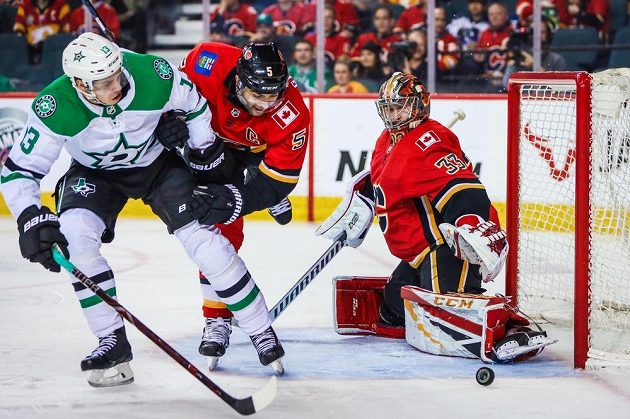 Brankář hokejistů Calgary Flames David Rittich sleduje, jak touš míjí jeho branku v utkání NHL.