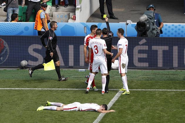 Sudí Mark Clattenburg ukazuje žlutou kartu Švýcarovi Fabianovi Scharovi za zákrok na Roberta Lewandowského (leží vpředu).