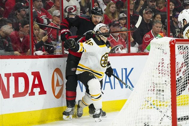 Hokejový útočník Bostonu David Krejčí (46) čelí drsnému ataku Nina Niederreitera z Caroliny Hurricanes v utkání play off NHL.