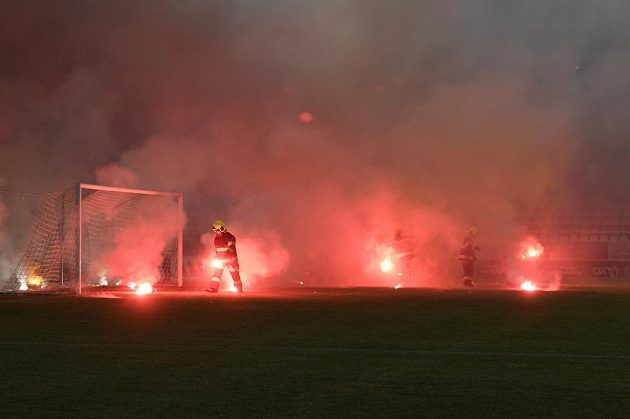 Hasiči sbírají z hřiště světlice, které tam v úvodu utkání naházeli fanoušci Sparty.