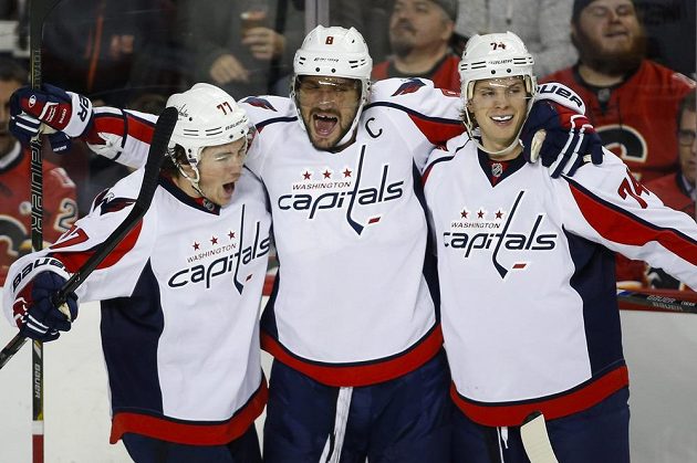 Kapitán Washingtonu Capitals Alexder Ovečkin (uprostřed) jásá se spoluhráči T. J. Oshiem (vlevo) a Johnem Carlsonem v utkání proti Calgary, v němž ruský útočník dosáhl na metu 900 bodů.