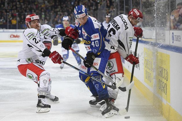 Tomi Sallinen (uprostřed) z Davosu bojuje o puk s královéhradeckými hráči Petrem Koukalem (vlevo) a Lukášem Vopelkou.