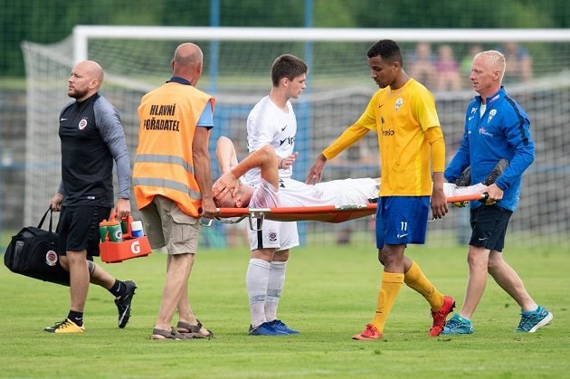 Faulující Michael Azillinon z Benešova utěšuje sparťana Uroše Radakoviče, který opouští hřiště na nosítkách.