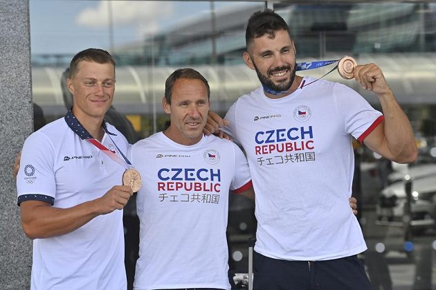 Deblkajakáři Josef Dostál (vpravo) a Radek Šlouf (vlevo) pózují fotografům s trenérem Karlem Leštinou (uprostřed) a bronzovými medailemi na Letišti Václava Havla v Praze po příletu z letních olympijských her v Tokiu.