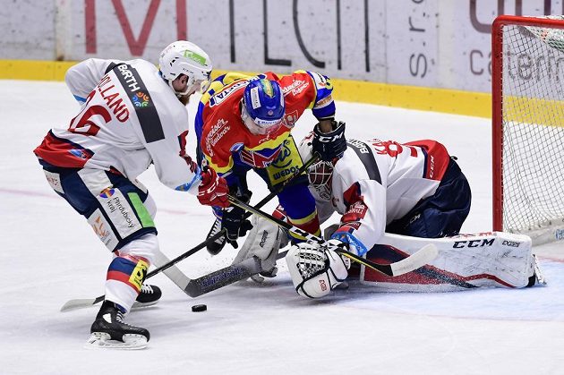 Zleva Rhett Holland a brankář Ondřej Kacetl z Pardubic a Zdeněk Doležal z Českých Budějovic (uprostřed) v akci během utkání baráže o hokejovou extraligu.