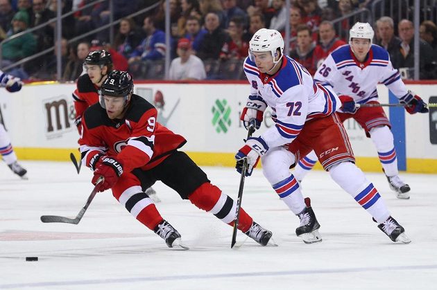 Křídelní útočník New Jersey Devils Taylor Hall (9) se snaží s pukem uniknout českému mladíkovi Filipu Chytilovi v barvách New Yorku Rangers během utkání NHL.
