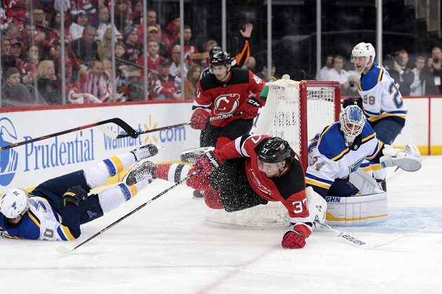 Souboj českého centra Pavla Zachy v dresu New Jersey (37) a švédského útočníka Oskar Sundqvista ze St. Louis (v bílém) během druhé třetiny zápasu NHL.