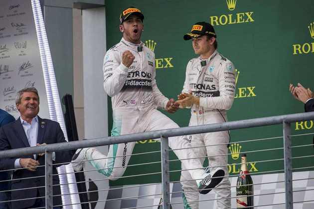 Lewis Hamilton juchá na pódiu v Austinu, Nico Rosberg s ledovým výrazem přihlíží.