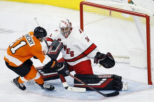 Hokejista Philadelphie Flyers Travis Konecny zakončuje útok těsně před Petrem Mrázkem z Caroliny.
