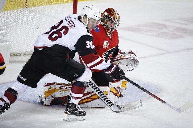 Hokejista Arizony Coyotes Christian Fischer v akci před brankou Davida Ritticha z týmu Calgary Flames.