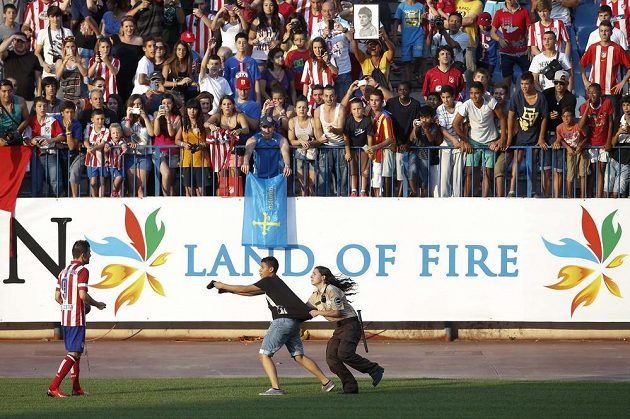 Ochranka se snaží zadržet fanouška, který se řítí k Davidu Villovi, jenž se představil příznivcům Atlétika v rámci mediální prezentace na stadiónu Vicente Calderóna v Madridu.