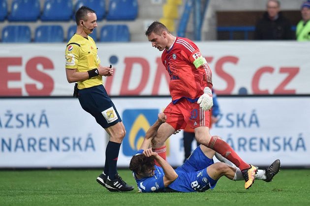 Liberecký útočník Matěj Pulkrab (v modrém dresu) leží na trávníku po zákroku olomouckého brankáře Miloše Buchty. Vlevo je rozhodčí Petr Ardeleánu.