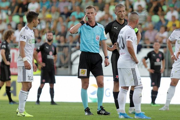 Sudí Jan Machálek komunikuje s videorozhodčím. Tomáš Souček ze Slavie následnou penaltu proti Karviné neproměnil.
