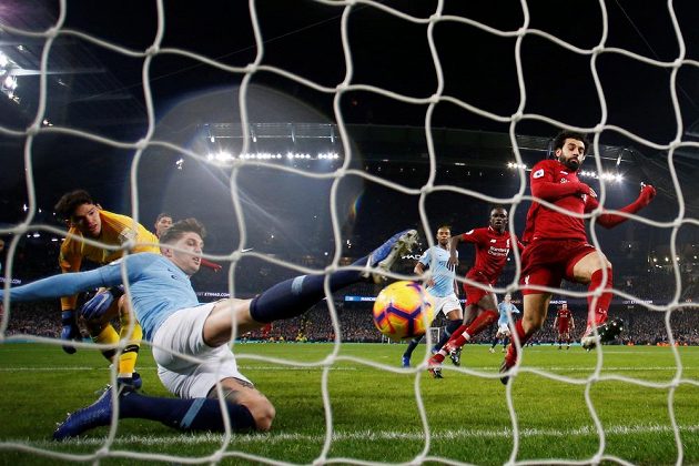 John Stones odvrací v pádu míč z brankové čáry před dotírajícím Mohamedem Salahem z Liverpoolu.