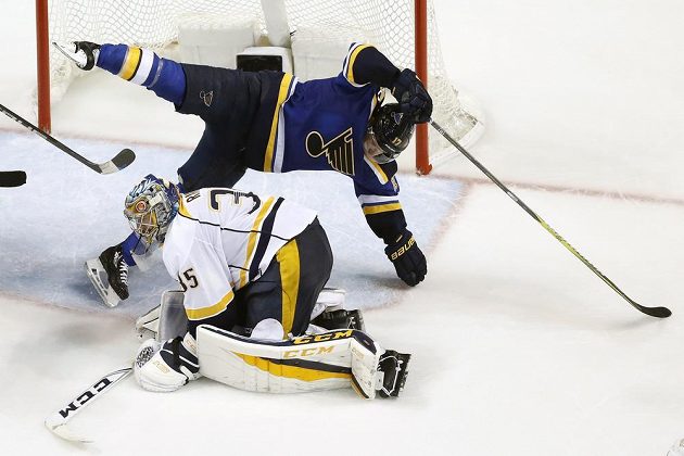 Forvard St. Louis Jaden Schwartz (17) padá po souboji s brankářem Nashvillu Pekka Rinnem (35).
