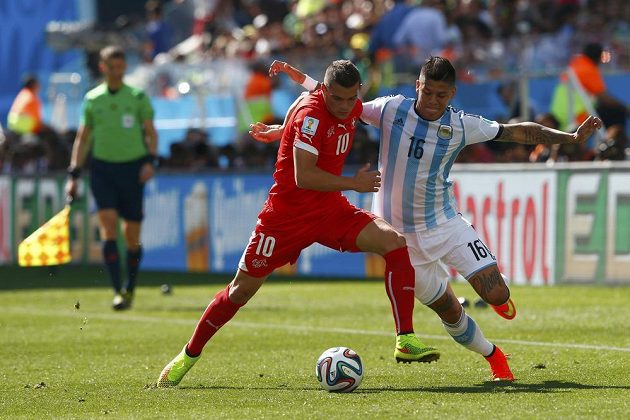 Švýcarský záložník Granit Xhaka (vlevo) nevyužil v prvním poločase velkou šanci. V tomto souboji bojuje o míč s argentinským obráncem Marcosem Rojem.