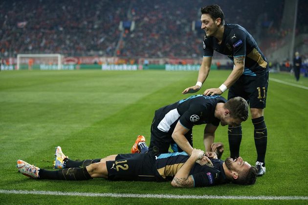 Olivier Giroud (ležící na zádech) z Arsenalu jásá po druhém gólu proti Olympiakosu, nad ním Aaron Ramsey a Mesut Özil