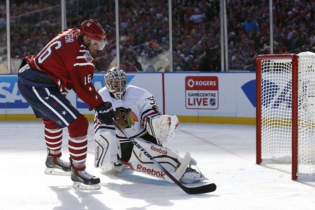 Útočník Washingtonu Capitals Eric Fehr (16) překonává brankáře Chicaga Coreyho Crawforda (50) během zápasu pod širým nebem.