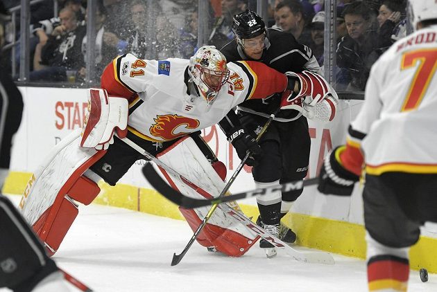 Brankář Calgary Flames Mike Smith se snaží za brankou zastavit centra Los Angeles Kings Trevora Lewise, který se hnal za pukem.